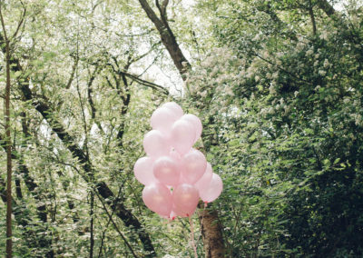family sat together in the ruff wood in north west with big bunch of pink balloons