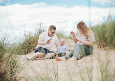 family sat waving on top of a sandhill in formby