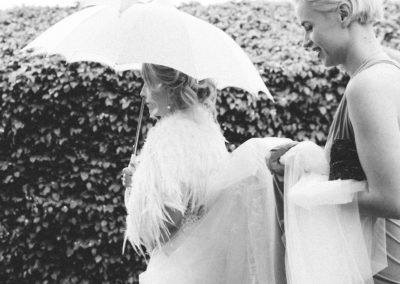 bride walking in rain with her dress being held up