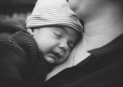 baby asleep on mother's shoulder wearing a winter hat